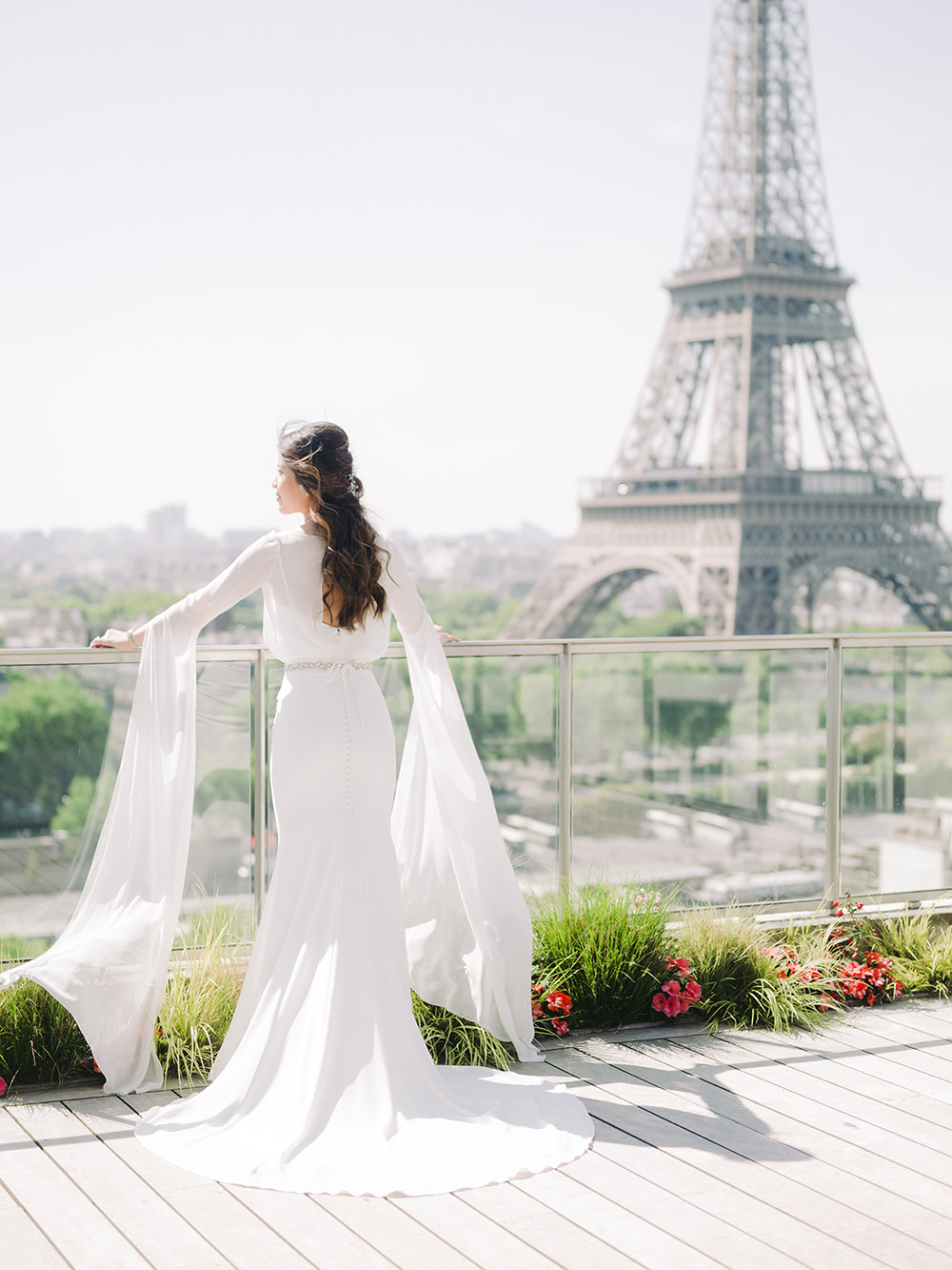  une mariée regarde la tour eiffel il y a du vent sur ses cheveux